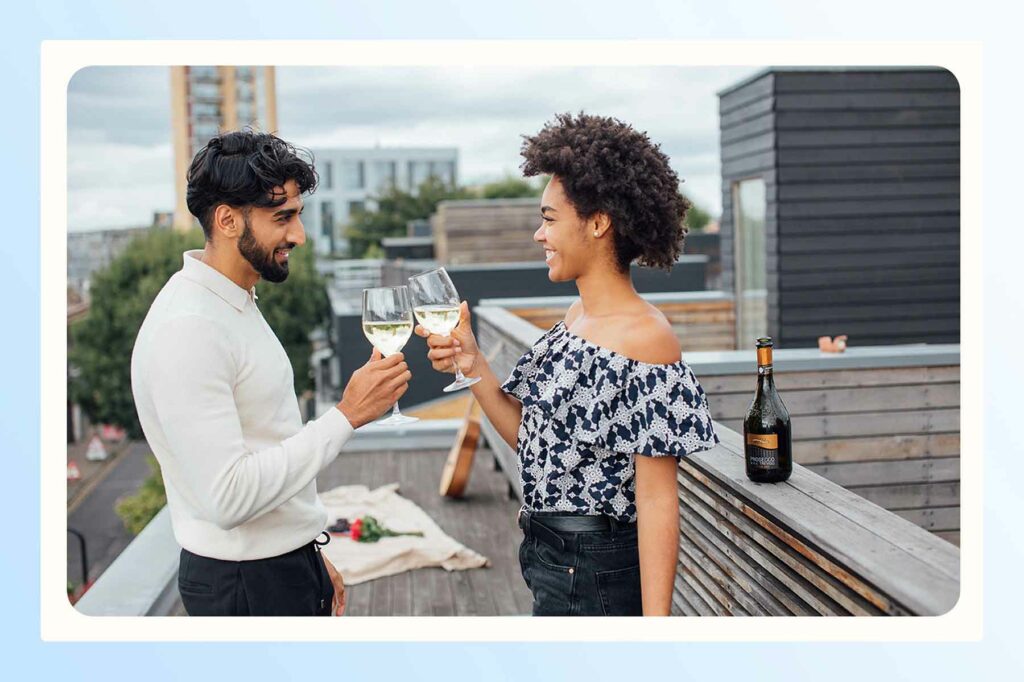 A couple clinking wine glasses while celebrating on a rooftop