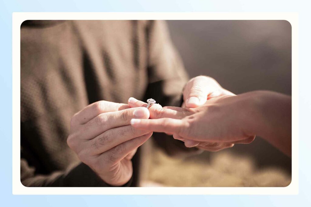 A man sliding an engagement ring on a woman's finger after a proposal