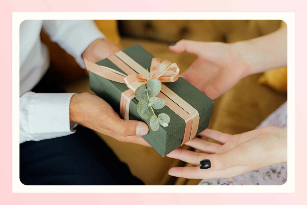Outstretched hands holding a wrapped engagement party gift and another set of hands accepting it